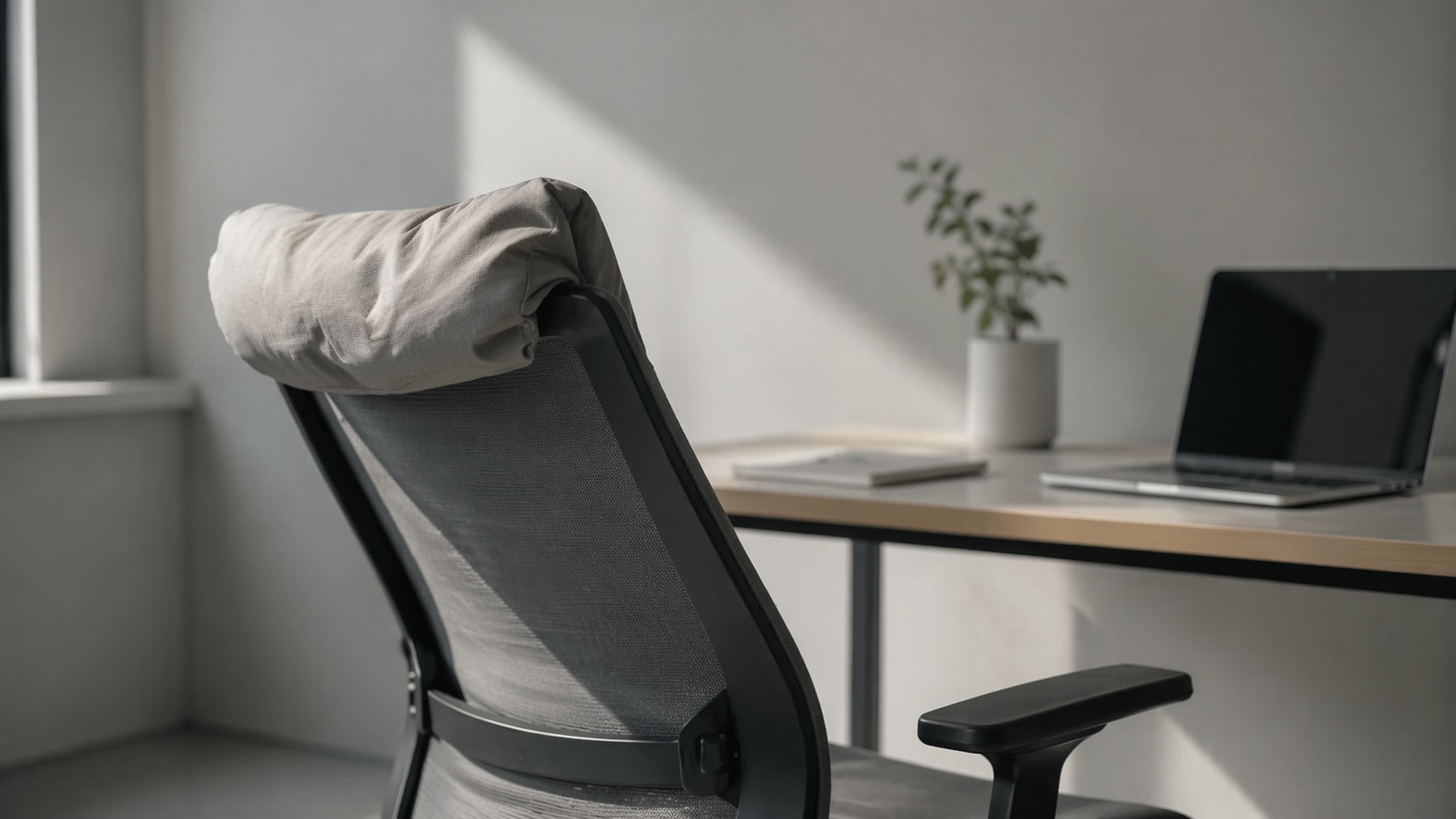 Minimalist office chair with compressed and misaligned headrest cushion, representing neck strain from prolonged desk posture.